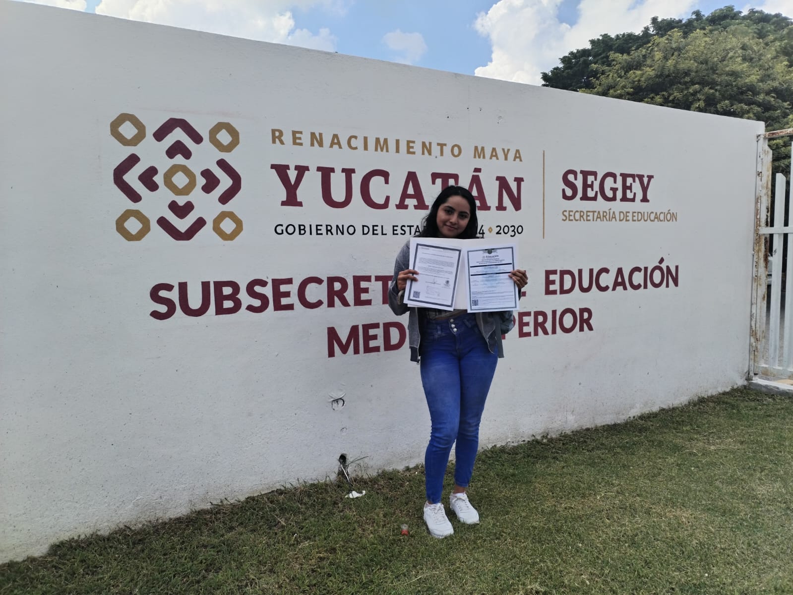 Alumna con su certificado frente a la Subsecretaría de Educación Media Superior de Yucatán